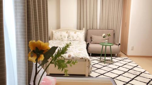 a small bedroom with a bed and a chair at Yuzuki Dome Osaka Kujo in Osaka
