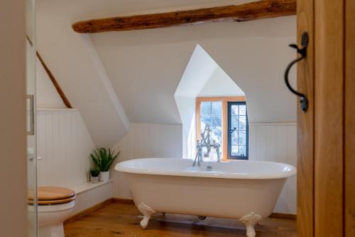 a bathroom with a white tub and a toilet at Stone Cottage in Stanton