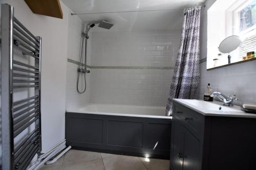 a bathroom with a bath tub and a sink at Down End Cottage, Corfe Castle in Corfe Castle