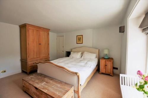 a bedroom with a large bed and a wooden cabinet at Down End Cottage, Corfe Castle in Corfe Castle