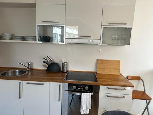 cocina con armarios blancos y encimera de madera en Marken Studio Apartments en Bergen