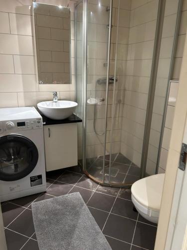 y baño con ducha, lavabo y lavadora. en Marken Studio Apartments en Bergen