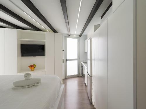 - une chambre avec des murs blancs, un lit et une télévision dans l'établissement Edison Penthouse By CanariasGetaway, à Las Palmas de Gran Canaria