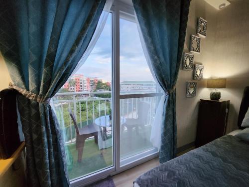 ein Schlafzimmer mit einem Fenster mit Blick auf einen Balkon in der Unterkunft Condo Azur Suites A326 Amani Resorts Residences , 5 minutes Airport, Netflix, Stylish, Cozy with Luxurious Swimming Pool in Pusok