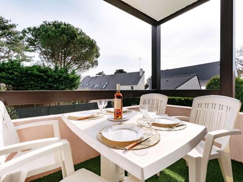 - une table blanche avec des chaises blanches et une bouteille de vin dans l'établissement Studio cabine à Carnac: 24m², proche plage/commerces, parking, balcon sud, petit animal ok - FR-1-477-108, à Carnac