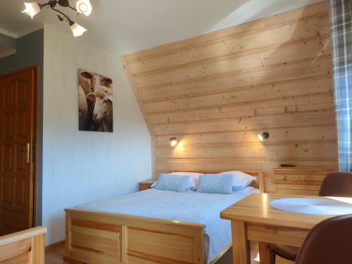 een slaapkamer met een bed en een houten muur bij Bafia - pokoje gościnne in Bukowina Tatrzańska
