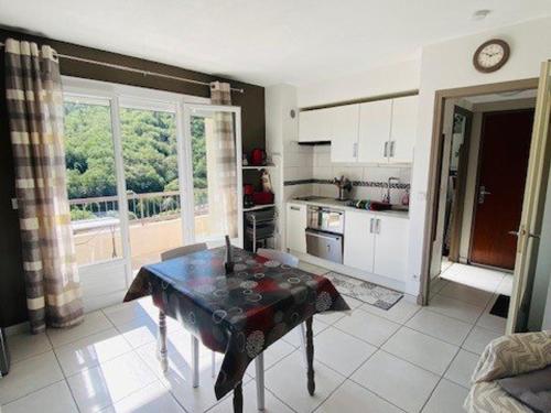 - une cuisine avec une table au milieu d'une pièce dans l'établissement Studio Confortable avec Balcon, Clim, Wi-Fi, Proche Thermes et Centre-ville, Animaux Bienvenus - FR-1-703-118, à Amélie-les-Bains-Palalda