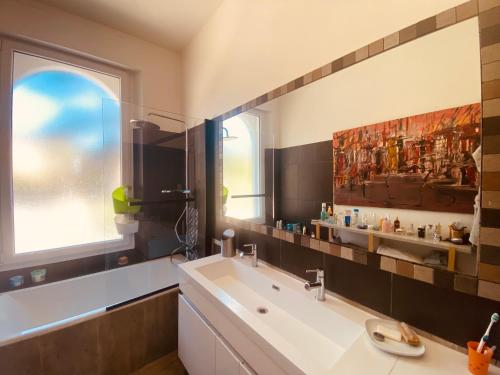 une salle de bain avec un lavabo et un grand miroir dans l'établissement Haut de Villa vue Mer, à La Ciotat