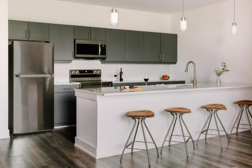 亞特蘭大的住宿－Sonder Midtown South，厨房配有绿色橱柜和带凳子的台面