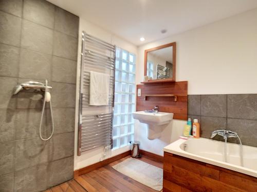 een badkamer met een bad, een wastafel en een douche bij Maison de vacances bord de mer in Plougrescant