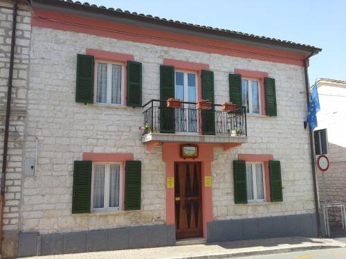 a building with green shutters and a balcony at Hotel Il Parco Sirolo in Sirolo