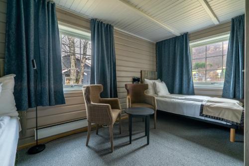 a bedroom with a bed and two chairs and a window at Vollan Gjestestue in Nordkjosbotn