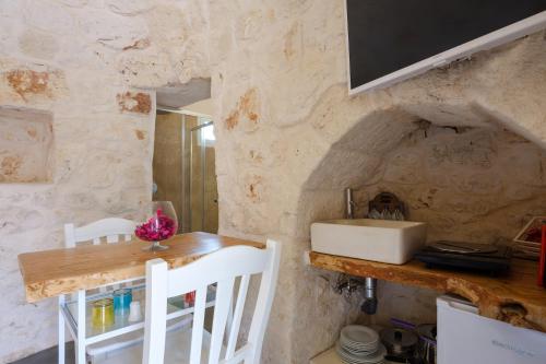 uma cozinha com uma mesa e um lavatório numa parede de pedra em Villa Stellina and Trullo Cecé em Ostuni