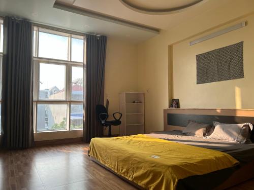 a bedroom with a yellow bed and a large window at S23 homestay in Hai Phong