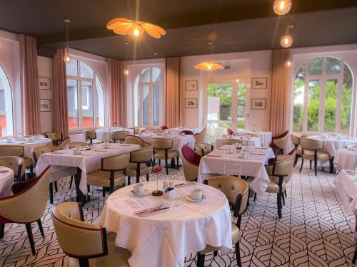 ein Esszimmer mit weißen Tischen und Stühlen und Fenstern in der Unterkunft Park Hotel Bellevue in Trégastel