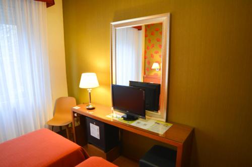 a hotel room with a desk with a computer and a mirror at eco Hotel Milano & BioRiso Restaurant in Milan