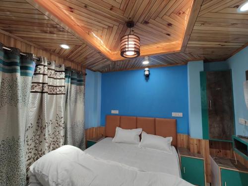 a bedroom with a bed and a blue wall at Alpine Valley Homestay in Shimla