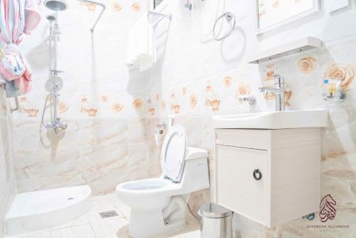 a bathroom with a toilet and a sink and a shower at فندق صحارى الفرسان in Şabyā