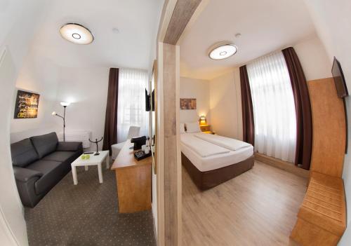 Habitación con baño con sofá y lavabo. en Hotel Goldenes Lamm, en Idstein