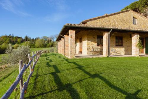 蒙特普齐亚诺Agriturismo Il Serraglio的一座古老的石头房子,在田野上设有围栏