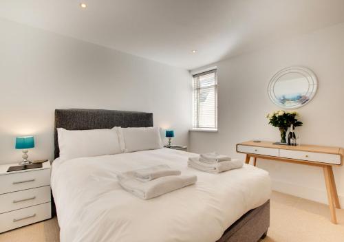 a bedroom with a large white bed and a desk at 3 Little Beach in Woolacombe