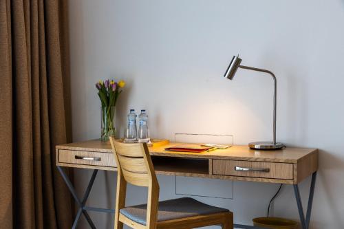 a wooden desk with a lamp and a vase of flowers at RAJ zdravia in Bratislava