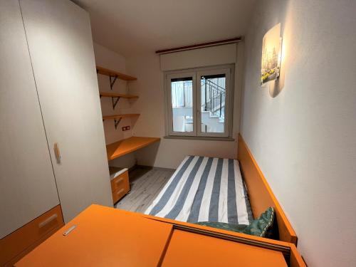een kleine kamer met een bed en een raam bij Nettuno in Grado