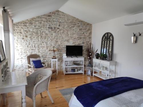 a bedroom with a stone wall with a bed and a tv at mas de manon in Valréas