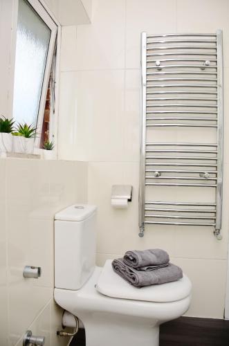 a bathroom with a toilet with a towel on it at 29EW Dreams Unlimited Serviced Accommodation- Staines - Heathrow in Stanwell