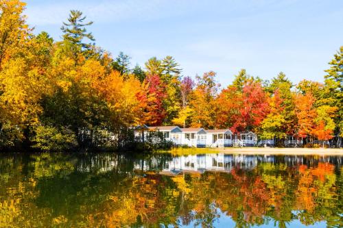 a house on the shore of a lake with autumn trees at Point Sebago Resort in Casco