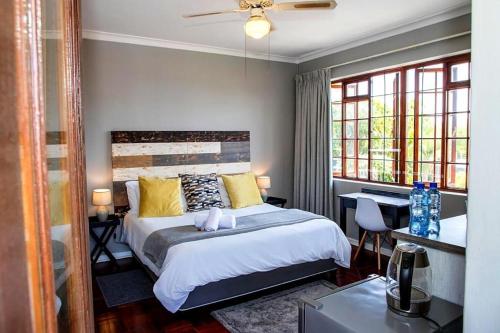 een slaapkamer met een bed, een bureau en ramen bij Boutique Hotel on the Bay in Humewood