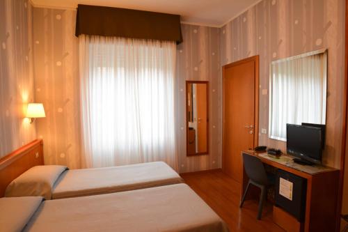 a hotel room with two beds and a desk and a television at eco Hotel Milano & BioRiso Restaurant in Milan