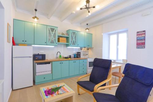 a kitchen with blue cabinets and two chairs and a table at Kaminaki Beachfront Apartments in Nisaki
