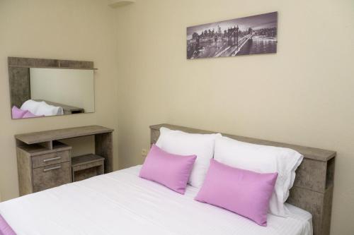 Schlafzimmer mit einem Bett mit lila Kissen und einem Spiegel in der Unterkunft Sunshine Apartments #01 in Thessaloniki