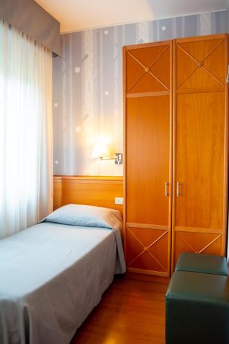 a bedroom with a bed and a large wooden cabinet at eco Hotel Milano & BioRiso Restaurant in Milan