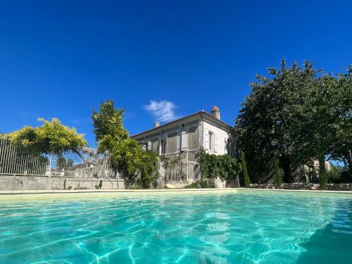 a pool of water with a house in the background at Chambres des Lunes in Aumagne