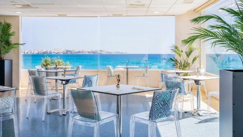 ein Restaurant mit Tischen und Stühlen und einem großen Fenster in der Unterkunft Hotel Spa Porta Maris by Melia in Alicante