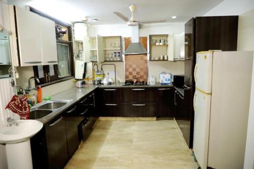 a kitchen with wooden cabinets and a white refrigerator at DIVINE INDIA SERVICE APARTMENT 3BHK, J-215 SAKET in New Delhi