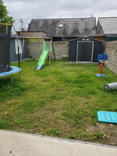 une cour avec une aire de jeux dotée d'un toboggan vert dans l'établissement proche circuit 24h du mans Maison 3 chambres, au Mans