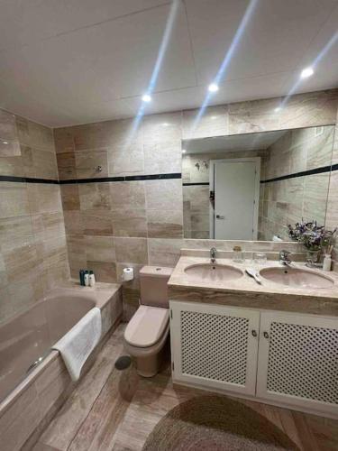 a bathroom with two sinks and a tub and a toilet at Sotogrande Marina Beach in Sotogrande