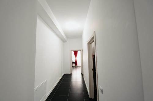 a hallway with white walls and a black tile floor at Cozy Aparthotel - Central City Suceava in Suceava