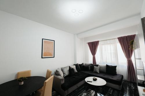 a living room with a black couch and a table at Cozy Aparthotel - Central City Suceava in Suceava