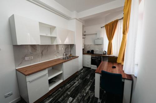 a kitchen with white cabinets and a wooden table at Cozy Aparthotel - Central City Suceava in Suceava