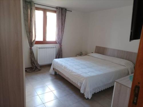 um quarto com uma cama branca e uma janela em Casa Fiori em Pisciotta