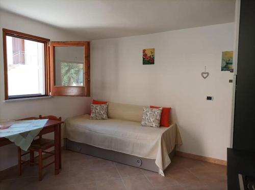 um quarto com uma cama, uma mesa e uma janela em Casa Fiori em Pisciotta