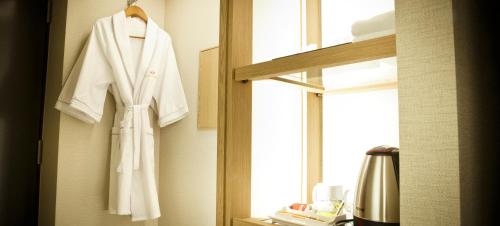 a white robe hanging on a window in a bathroom at Ariana Hotel in Daegu