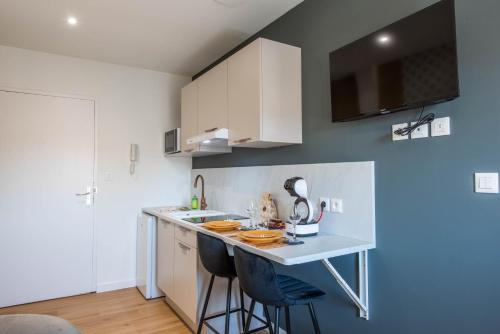 a kitchen with white cabinets and a counter with stools at WelcomeAgen - Al Capone - Clim - Wifi Fibre - Cosy in Agen