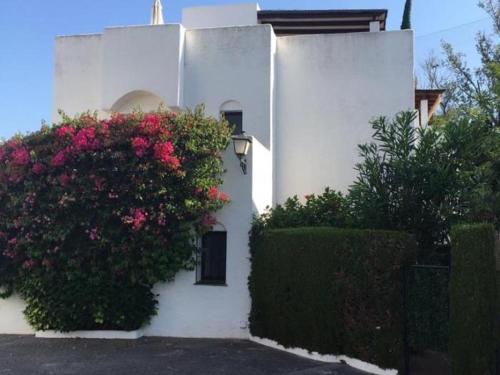 Una casa blanca con flores a un lado. en Homey Home Guadalvillas 91 en Marbella