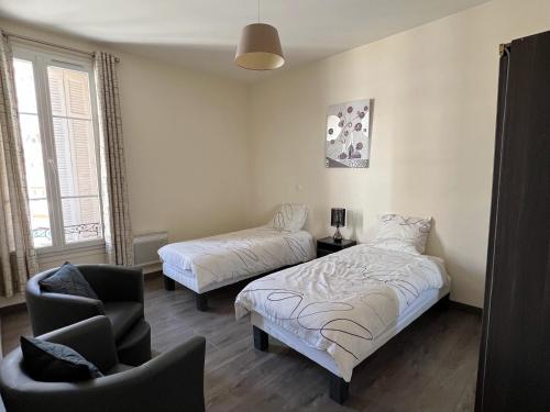 une chambre avec deux lits et une chaise dedans dans l'établissement Cannes Centre, 3 Chambres, Plage et La Croisette à 50m, à Cannes