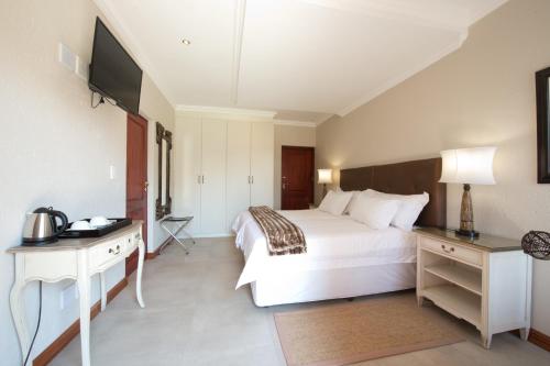 a bedroom with a white bed and a television at The Finches Nest in  Hammanskraal 